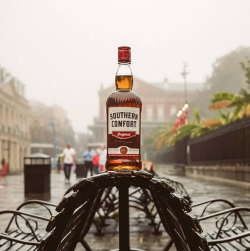 southern comfort bottle with american flag behind it and firewood under it